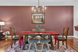 A dining room with a wooden table, chairs, a chandelier, and a mirror on the wall. - Venus 142 2 Bedroom Condo (Gatlinburg)