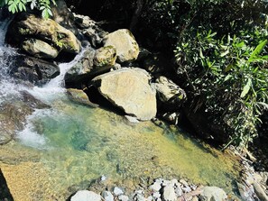 A clear stream flowing over rocks with clear water, surrounded by greenery. - Creekvista Vista y Encanto del Charco (Cocorná)