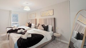 Un dormitorio moderno con una cama grande, dos mesitas de noche y un espejo.