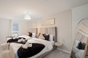A modern bedroom with a large bed, two bedside tables, and a mirror.