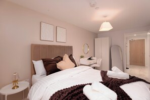 Une chambre d’hôtel moderne équipée d’un lit, d’une table de chevet, d’une lampe et d’un miroir.