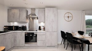 Una cocina moderna con una isla central, electrodomésticos integrados y una zona de comedor con una mesa redonda y sillas.