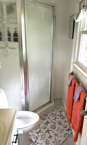 Een badkamer met een douchecabine van glas, een toilet en een wastafel.