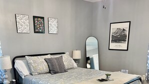 Un dormitorio con cama, mesita de noche, lámpara, espejo y alfombra.