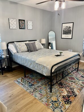 Une chambre à coucher avec un lit, une table de chevet, une lampe, un miroir et un tapis.