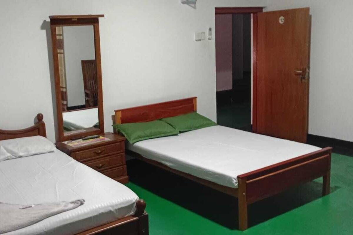 A bedroom with a bed, a dresser, a mirror, and a door.