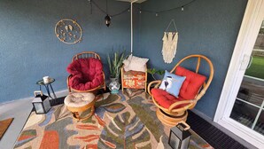 Um quarto acolhedor com cadeiras de vime, um tapete estampado e luzes de fada.
