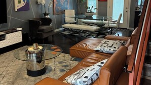 A modern living room with a leather sofa, a glass coffee table, and a dining area with a glass table.