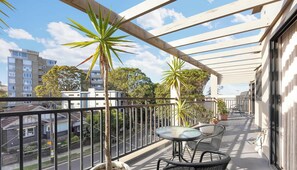 A balcony with a table and chairs, potted plants, and a view of buildings and trees. - MetaWiseBnB 2BR Penthouse style near Bondi Beach & Westfield (Bondi Junction)