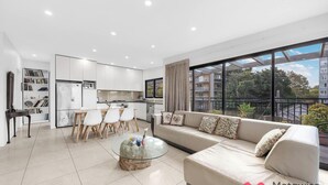 A modern apartment with a dining area, kitchen, living room, and large windows offering a view of the city. - MetaWiseBnB Bondi Junction Penthouse Style (Bondi Junction)