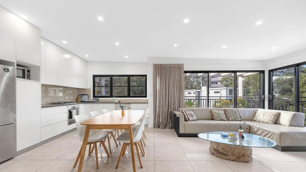 A modern kitchen with white cabinets, a dining table with chairs, a sofa, and a coffee table. - MetaWiseBnB Bondi Junction Penthouse Style (Bondi Junction)