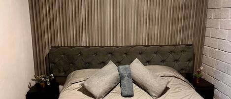 A bed with a tufted headboard, a neutral-toned bedspread, and two pillows.