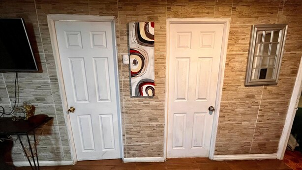 Drei weiße Türen mit modernem Design, ein an der Wand befestigtes abstraktes Kunstwerk und ein kleines Fenster mit Gittermuster.