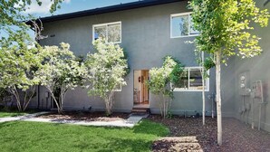A modern building with a grey exterior, a well-maintained lawn, and several trees. - Spacious home near town w/ private hot tub- next to trails & river (Ketchum)