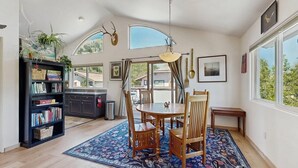 A dining area with a round table, chairs, a rug, and a bookshelf. - Spacious home near town w/ private hot tub- next to trails & river (Ketchum)