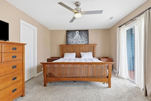 A bedroom with a wooden bed, a ceiling fan, a dresser, and a painting on the wall.