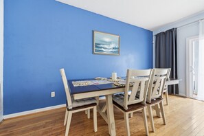 A dining area with a blue wall, wooden floor, and a table with chairs.