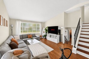 A living room with a sofa, coffee table, TV, and exercise bike.