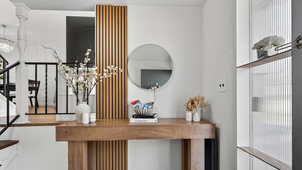 Una consola de madera con un espejo, libros y objetos decorativos.