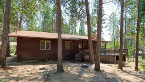 Eine Holzhütte mit verdeckter Veranda und einer Treppe zu einer Terrasse.