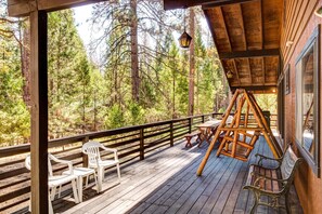 A wooden deck with a swing set, outdoor seating, and a view of a forest. - (42A) Megan's Retreat at The Redwoods in Yosemite (Yosemite National Park)