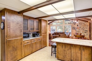 A kitchen with wooden cabinets, a microwave, and a stone wall. - (42A) Megan's Retreat at The Redwoods in Yosemite (Yosemite National Park)