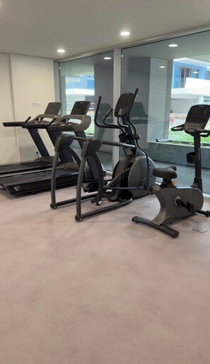 A gym with exercise equipment, including treadmills and stationary bikes, and large windows with a view of the outside. - Sal Douro Golden | Sea View and Comfort (Vila Nova de Gaia)