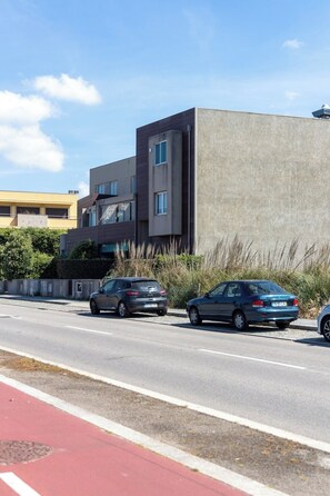 A modern building with a flat roof, a concrete facade, and a red bike lane. - Blue Frame | Ocean front (Vila Nova de Gaia)