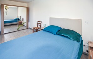 A bedroom with a bed, a chair, a mirror, and a bedside table. - Beautiful home in Gras (Gras)