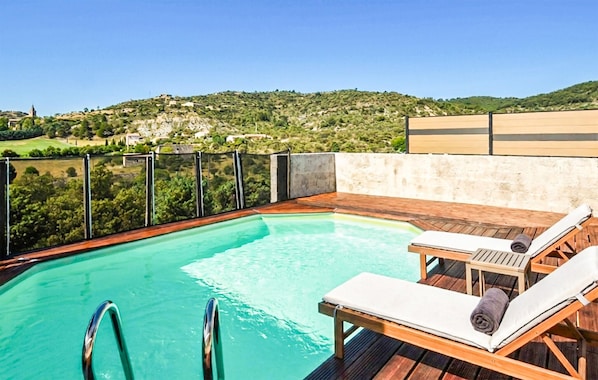 A rooftop pool with wooden deck, lounge chairs, and a view of a green landscape. - Beautiful home in Gras (Gras)