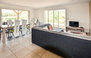 A modern living room with a large sofa, a dining area with chairs, a TV, and a balcony with a view. - Beautiful home in Gras (Gras)