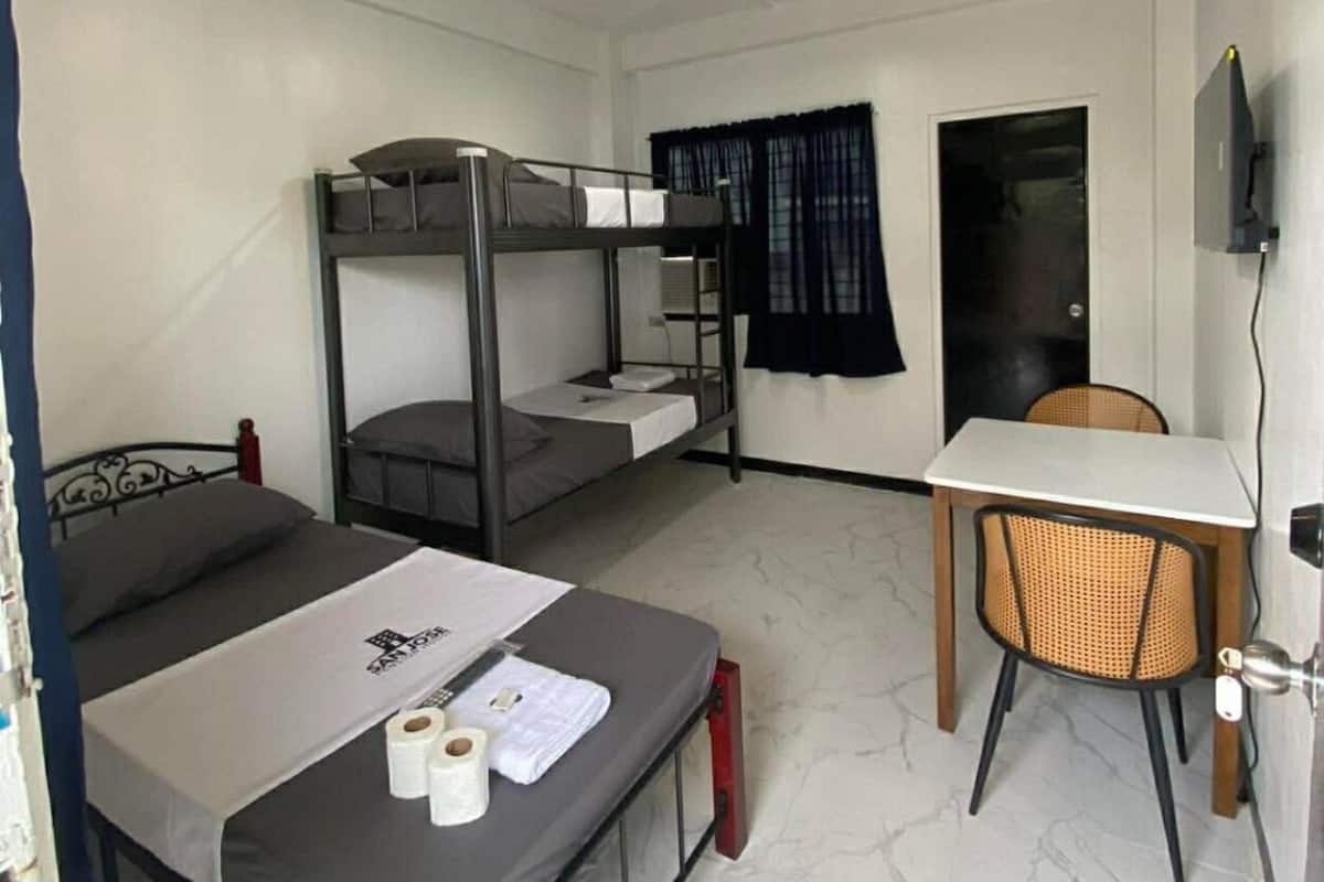Ein Schlafsaalzimmer mit Etagenbetten, einem Schreibtisch, einem Stuhl und einem Fernseher.