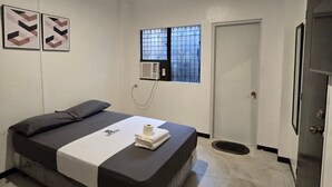 Una camera da letto con un letto, una finestra con sbarre, un condizionatore d'aria e una porta.