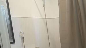 Una doccia con soffione a mano e rubinetto montato a parete.