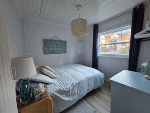 A bedroom with a bed, bedside lamp, and a hanging light fixture.
