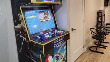 Une borne d’arcade avec un décor inspiré de l’univers de Mario, une porte et une pile de magazines.