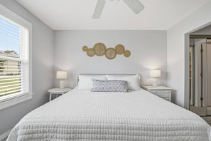 Ein Schlafzimmer mit einem großen Bett, zwei Nachttischen, einem Deckenventilator und einem an der Wand befestigten Dekoelement.
