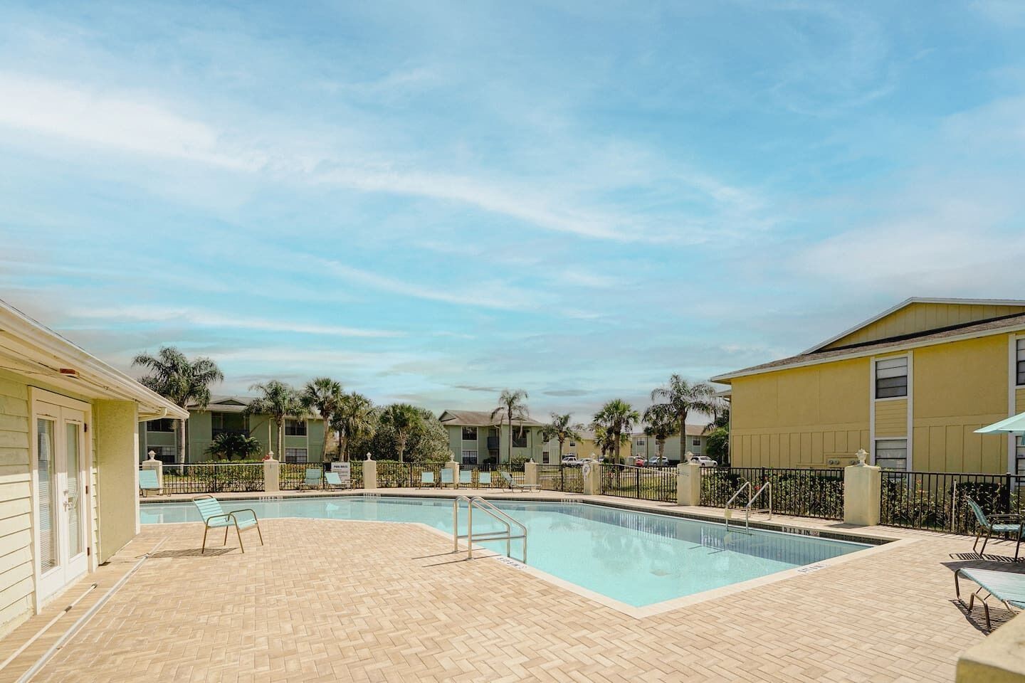 A swimming pool with a brick deck, surrounded by buildings with a uniform architectural style.