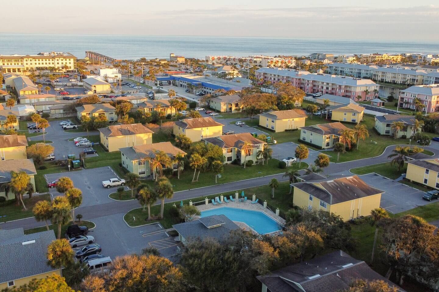 A coastal residential area with multiple-story buildings, a swimming pool, and a view of the ocean.
