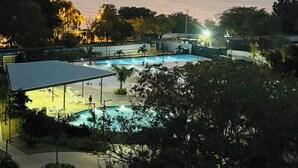 A resort with a pool, a view of the sea, and a tall building in the background. - Apartament With View at the sea Close at the Airport (Santa Marta)