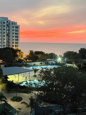 A resort with a swimming pool, a covered area, and a view of the ocean at sunset. - Modern Beachfront Loft in Santa Marta (Santa Marta)