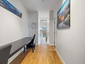 A hallway with a bench, wooden flooring, and two large landscape paintings on the walls. - Iconic Lake View Apt | Ski Lockers (Queenstown)