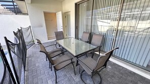 Een tafel met glazen blad en zes stoelen, een deur en een schuifpui.