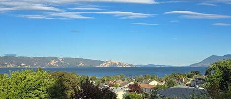 Un área residencial costera con casas, cielo despejado y montañas al fondo.