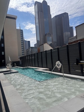 Ein Pool auf dem Dach mit klarem Wasser, umgeben von hohen Gebäuden.