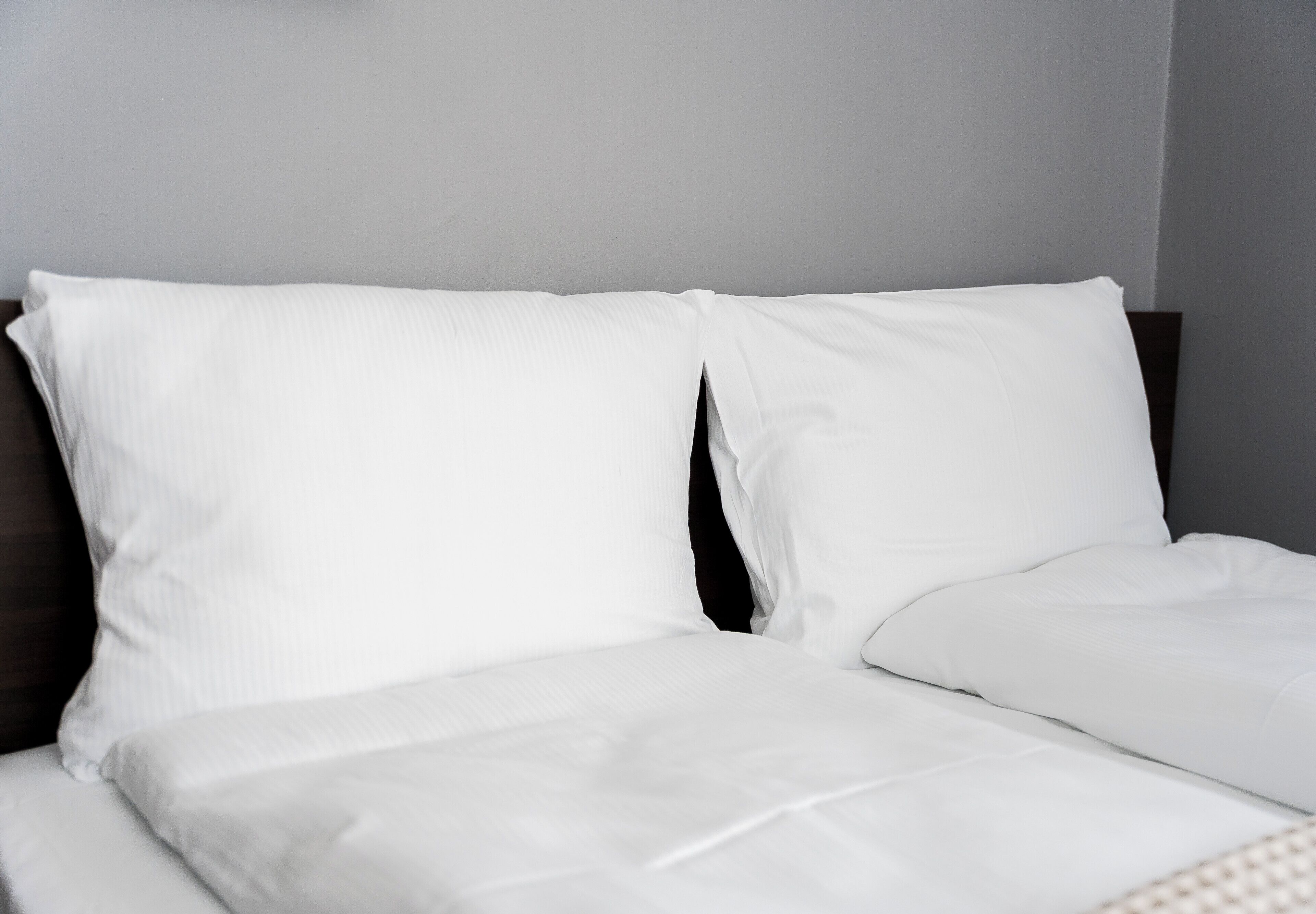 Un letto con biancheria da letto bianca e una testiera scura.