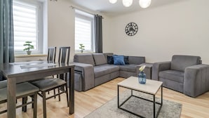 Una sala de estar moderna con un sofá seccional, una mesa de comedor con sillas y una mesa de centro.