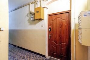 Ein Flur mit einer Holztür, einem Verteilerkasten und einem an der Wand montierten Thermostat.