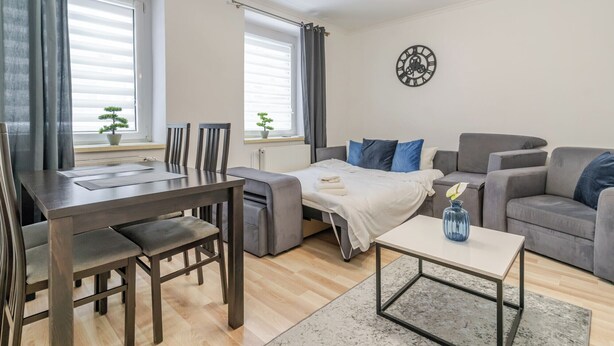 Una sala de estar moderna con un sofá, una mesa de comedor con sillas, una mesa de centro y un reloj en la pared.