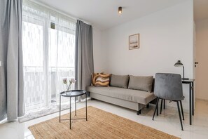 Un salon moderne avec un canapé, une petite table, un fauteuil et une lampe.